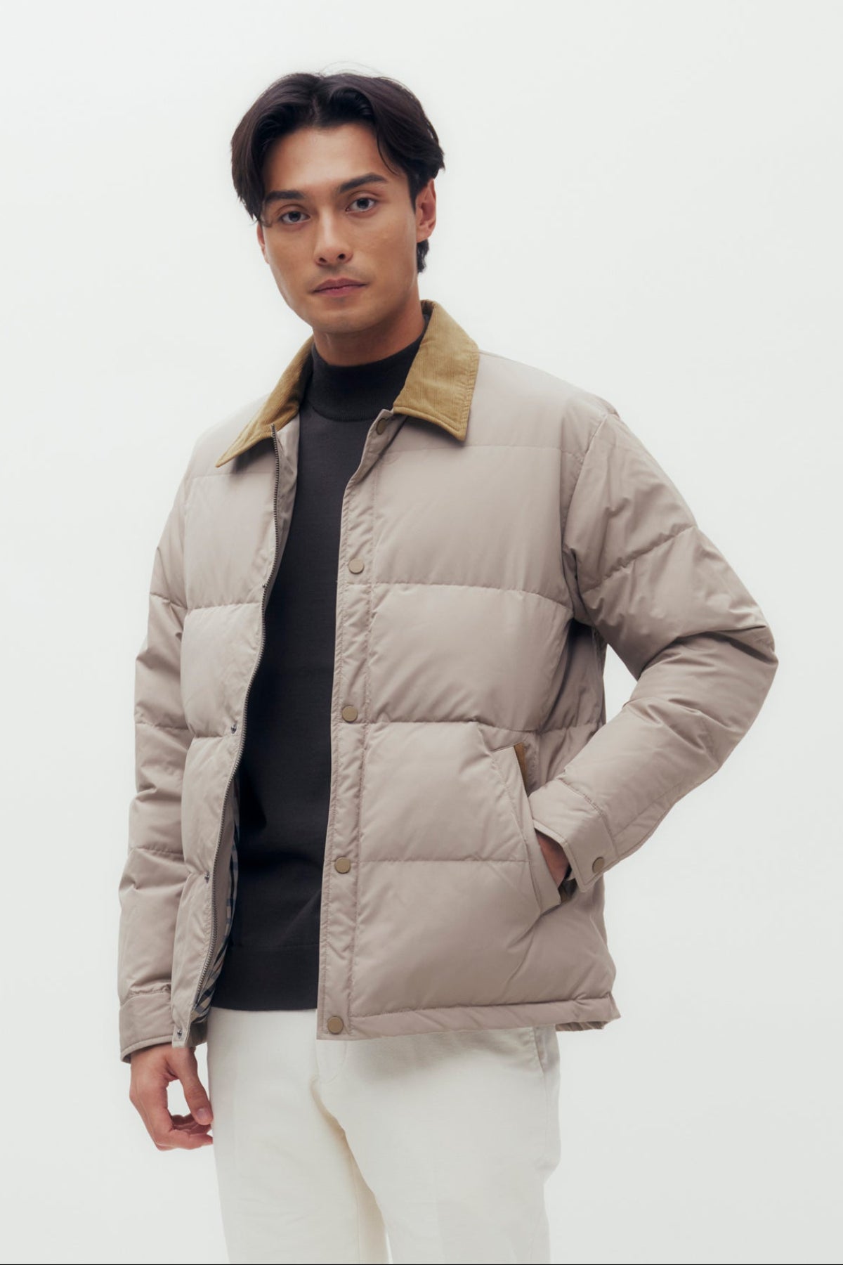 Man wearing a beige puffer jacket with a brown collar on a white background